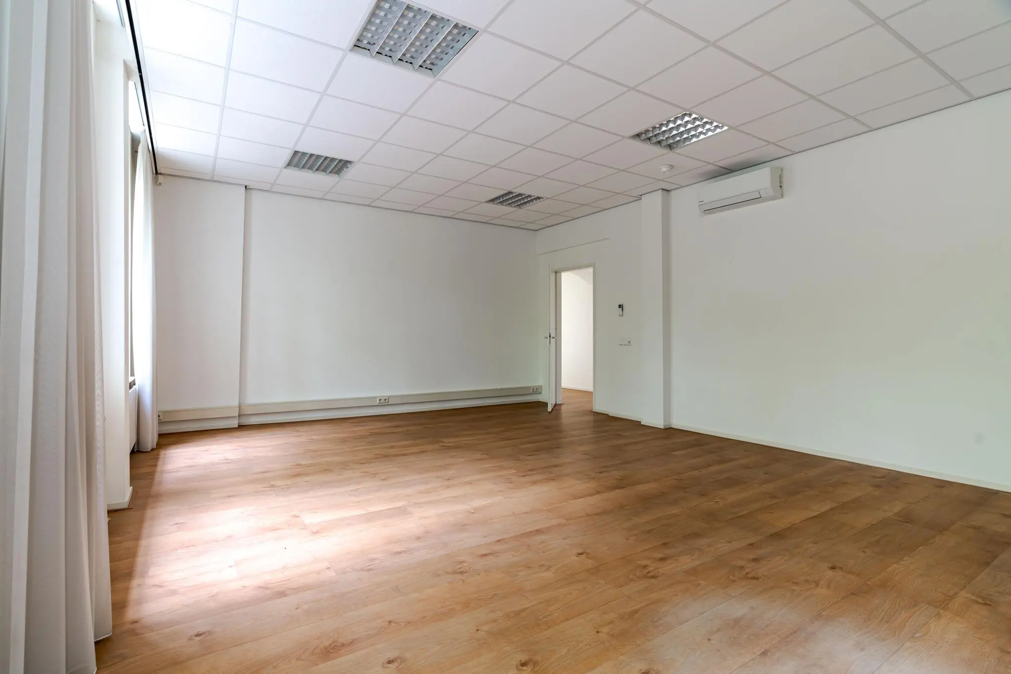 Lege kantoorruimte aan het Lange Voorhout met houten vloer, systeemplafond en airconditioning.